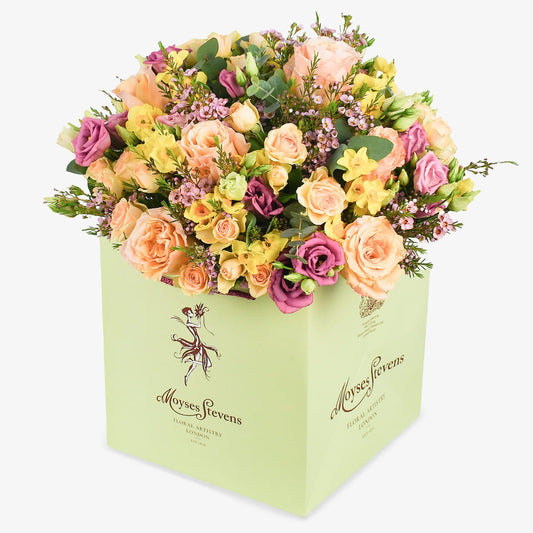 Peach Heirloom luxury flower bouquet by Moyses Stevens UAE featuring ruffled peach petals with the deep, saturated hues of fragrant lisianthus. Accented with the dainty charm of spring bulbs and ethereal pink waxflower.